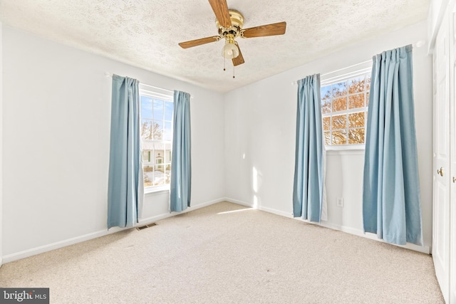 carpeted empty room featuring ceiling fan and a textured ceiling