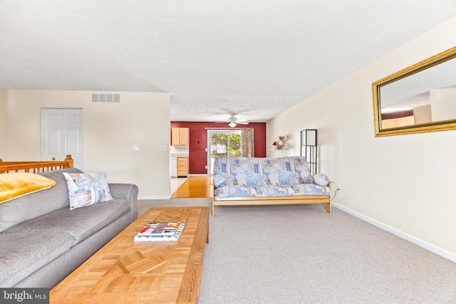 living room featuring a textured ceiling, carpet floors, and ceiling fan