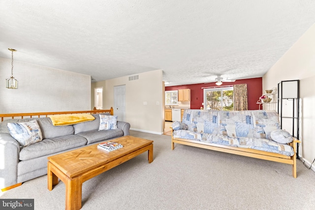 living room with a textured ceiling, carpet floors, and ceiling fan