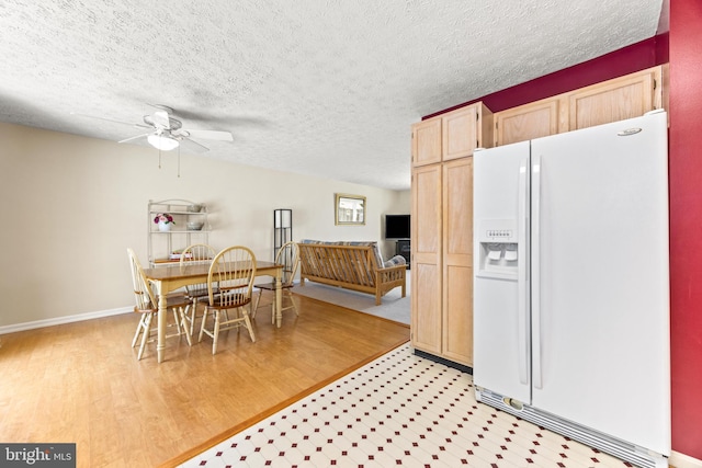 interior space with ceiling fan, white fridge with ice dispenser, light hardwood / wood-style floors, a textured ceiling, and light brown cabinetry