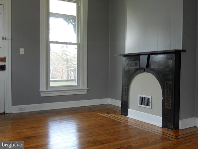 unfurnished living room featuring plenty of natural light and wood-type flooring