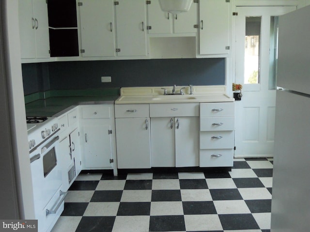 kitchen with stainless steel fridge, white range oven, white cabinetry, and sink