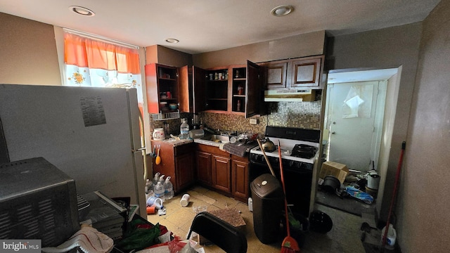 kitchen with decorative backsplash, black range oven, and white fridge