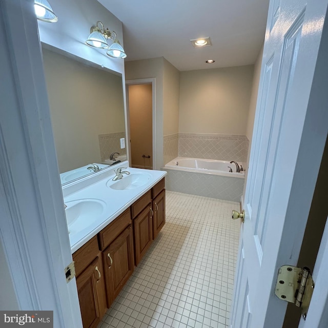 bathroom with tile patterned floors, vanity, and tiled bath