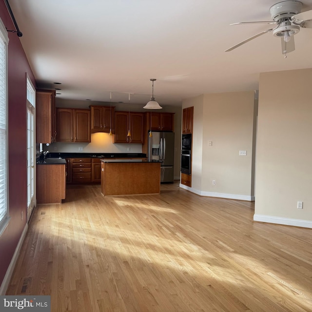 kitchen featuring ceiling fan, pendant lighting, light hardwood / wood-style flooring, stainless steel fridge with ice dispenser, and a kitchen island