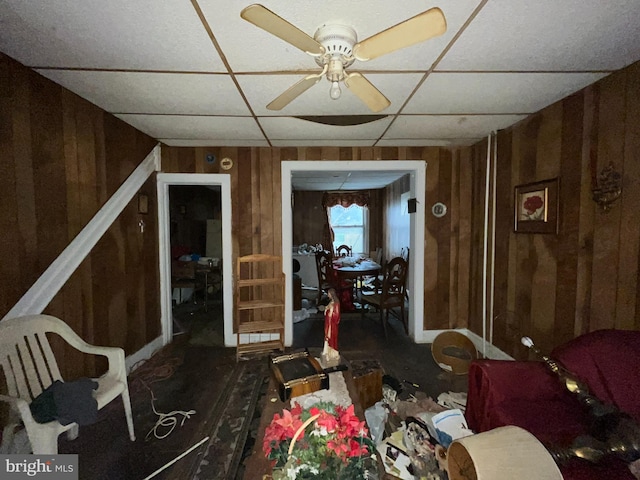 interior space with ceiling fan and wooden walls