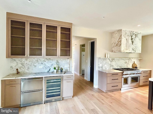 kitchen featuring range with two ovens, light hardwood / wood-style flooring, wine cooler, and decorative backsplash