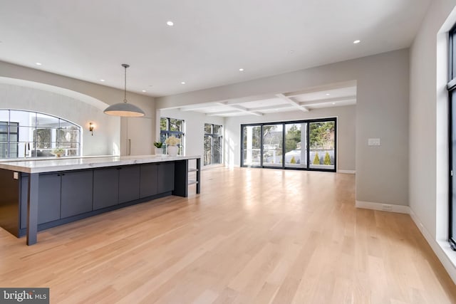 kitchen with pendant lighting, a spacious island, light hardwood / wood-style floors, and beamed ceiling