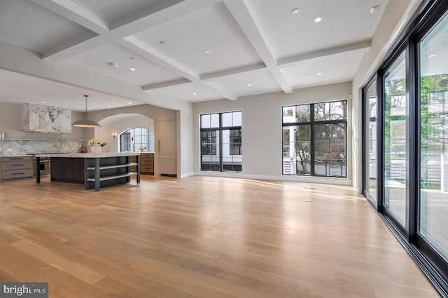 living room featuring beamed ceiling, a wealth of natural light, and light hardwood / wood-style flooring