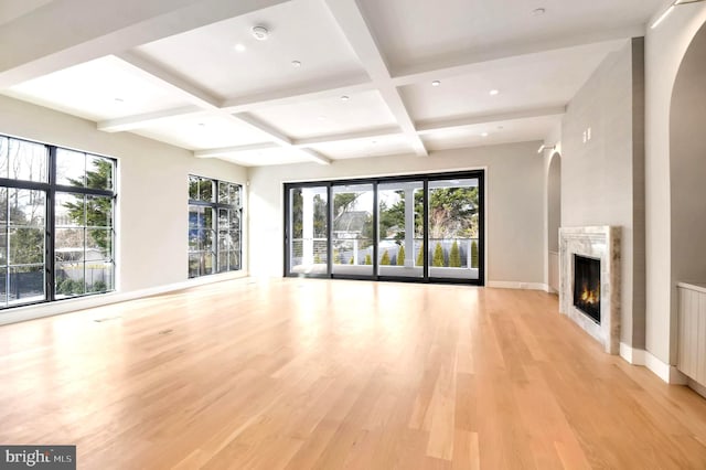 unfurnished living room featuring beam ceiling, coffered ceiling, light wood-type flooring, and a high end fireplace