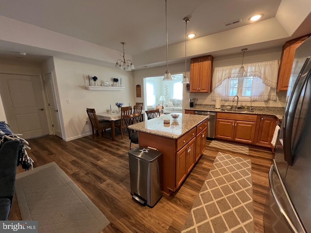 kitchen featuring pendant lighting, a center island, stainless steel appliances, and a raised ceiling