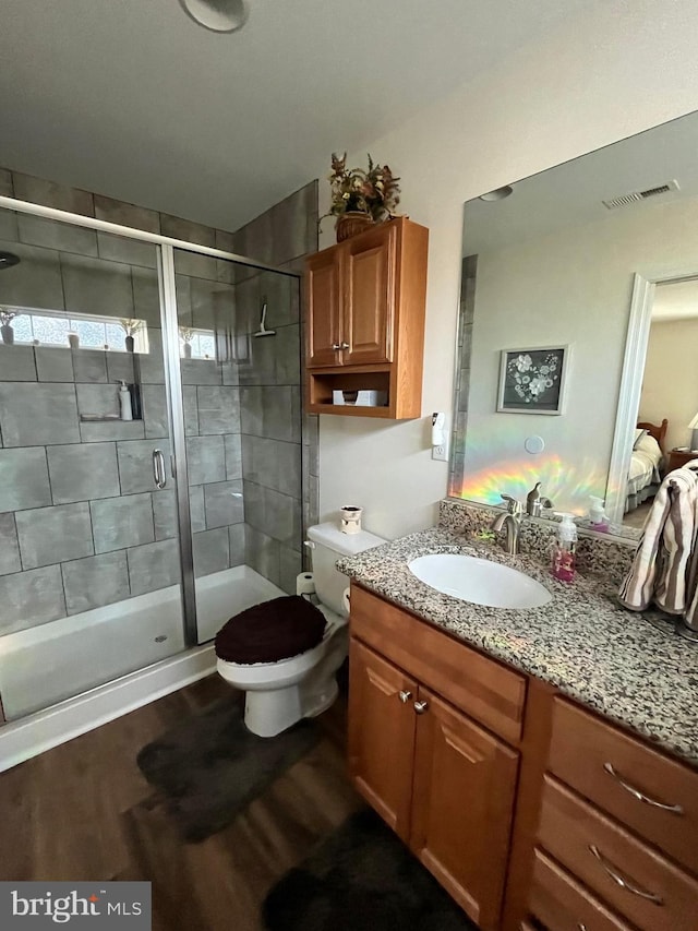 bathroom featuring hardwood / wood-style floors, vanity, toilet, and an enclosed shower