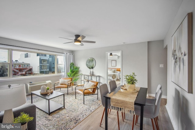 living room featuring light wood-type flooring, a wall mounted AC, and ceiling fan