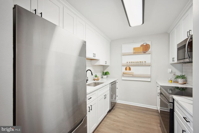 kitchen with sink, white cabinetry, stainless steel appliances, and light hardwood / wood-style flooring