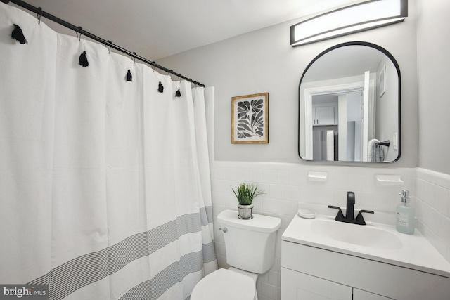 bathroom with vanity, tile walls, and toilet