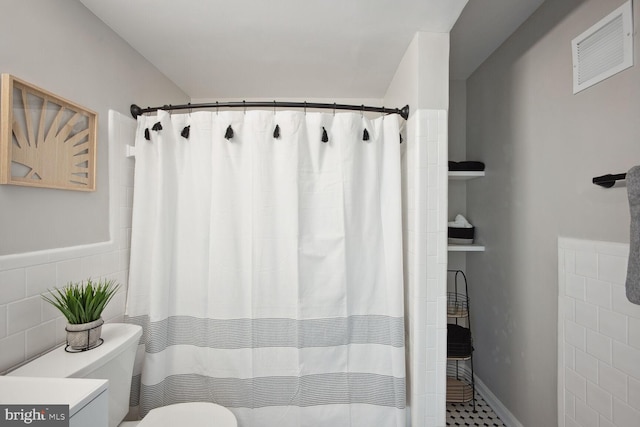 bathroom with curtained shower, tile walls, and toilet