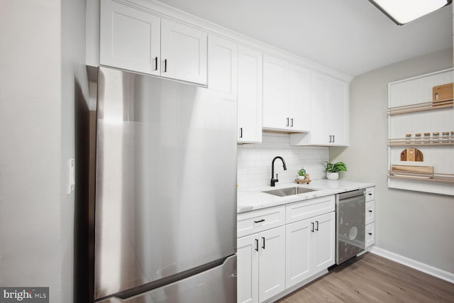 kitchen featuring sink, light hardwood / wood-style flooring, light stone counters, white cabinetry, and stainless steel appliances