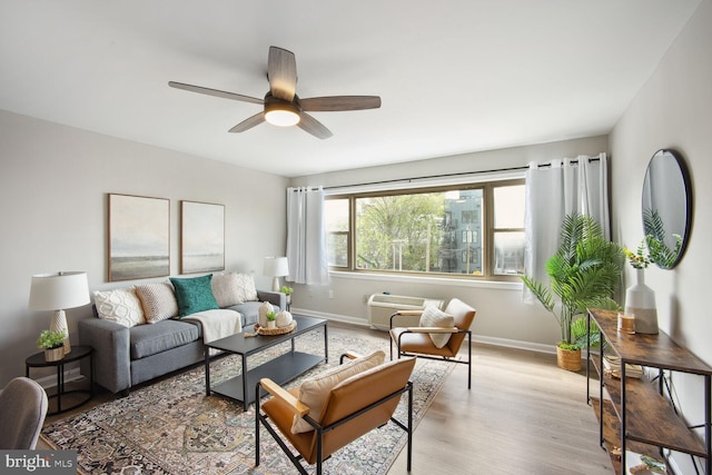 living room featuring a wall unit AC, ceiling fan, and light wood-type flooring