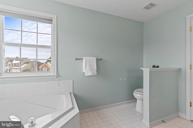 bathroom featuring a relaxing tiled tub, toilet, and tile patterned flooring