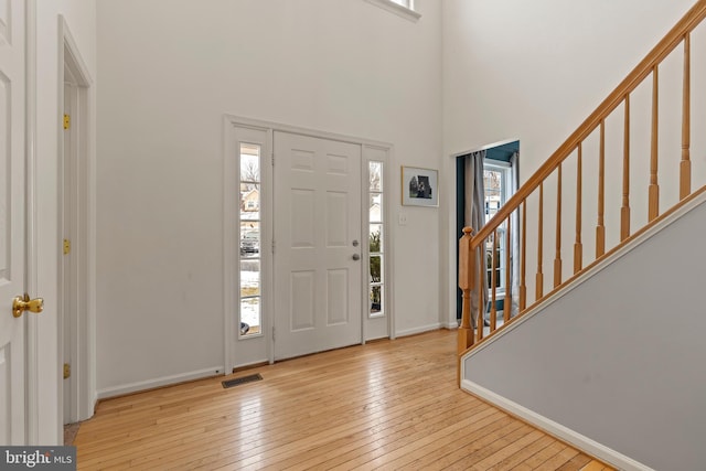 foyer entrance with a towering ceiling and light hardwood / wood-style floors