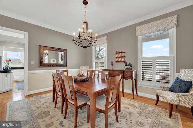 dining area with light wood-type flooring, an inviting chandelier, and ornamental molding