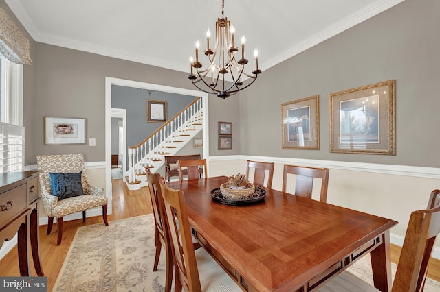 dining room with light wood-type flooring, an inviting chandelier, and ornamental molding