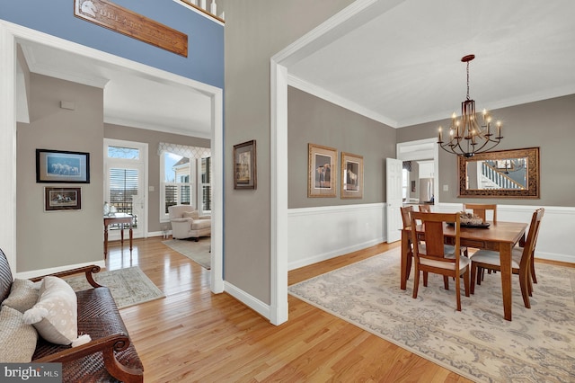 dining area featuring crown molding, an inviting chandelier, and light hardwood / wood-style flooring