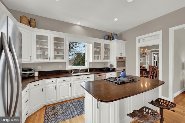 kitchen featuring white cabinetry, appliances with stainless steel finishes, a center island, and light wood-type flooring