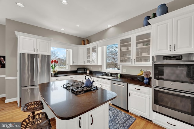 kitchen with a center island, white cabinets, light hardwood / wood-style flooring, and stainless steel appliances