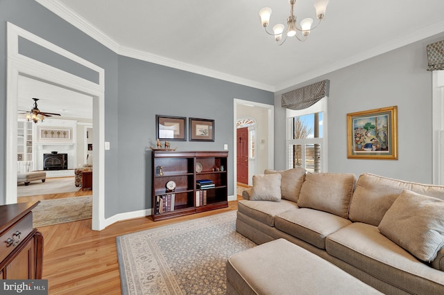 living room with a wood stove, ceiling fan with notable chandelier, ornamental molding, and light hardwood / wood-style floors