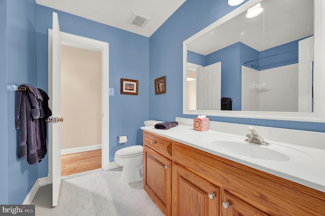 bathroom featuring walk in shower, vanity, tile patterned floors, and toilet