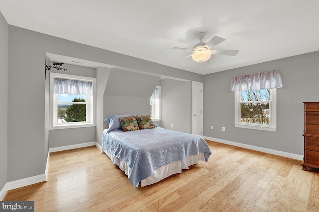 bedroom featuring ceiling fan, multiple windows, and light wood-type flooring