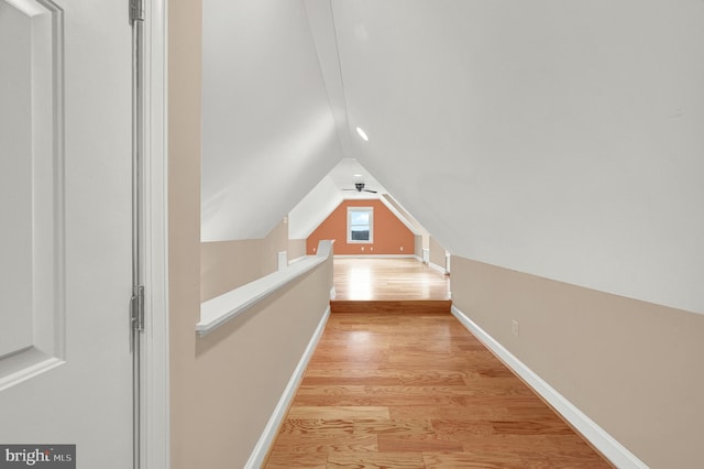 hallway with vaulted ceiling and light hardwood / wood-style flooring