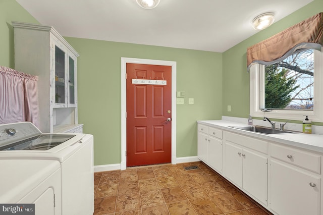 clothes washing area featuring cabinets, washer and clothes dryer, and sink