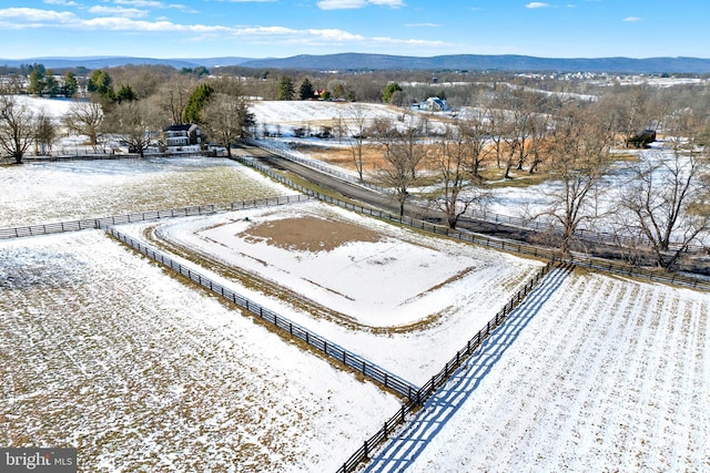 snowy aerial view featuring a rural view and a mountain view