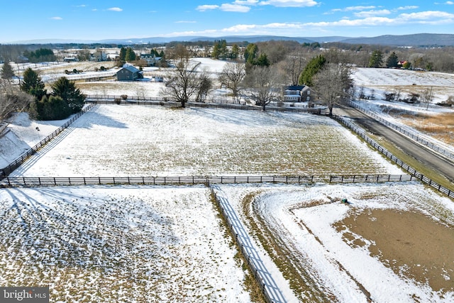 snowy aerial view with a rural view and a mountain view