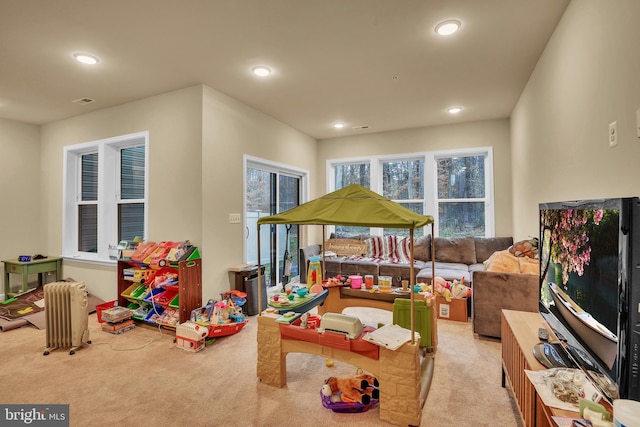 recreation room featuring radiator heating unit and light carpet