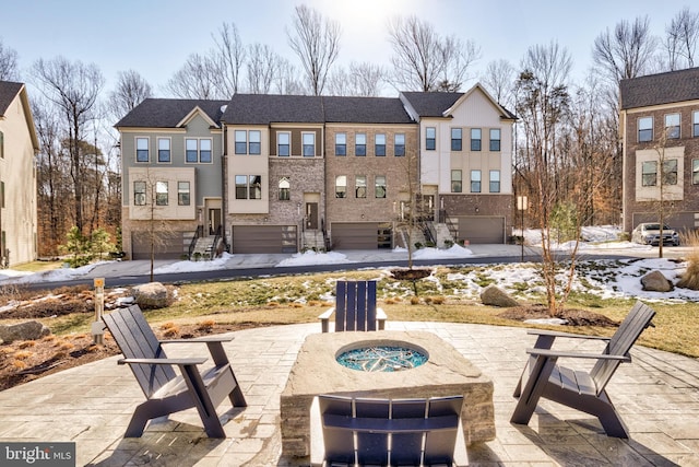 rear view of house with a garage and an outdoor fire pit