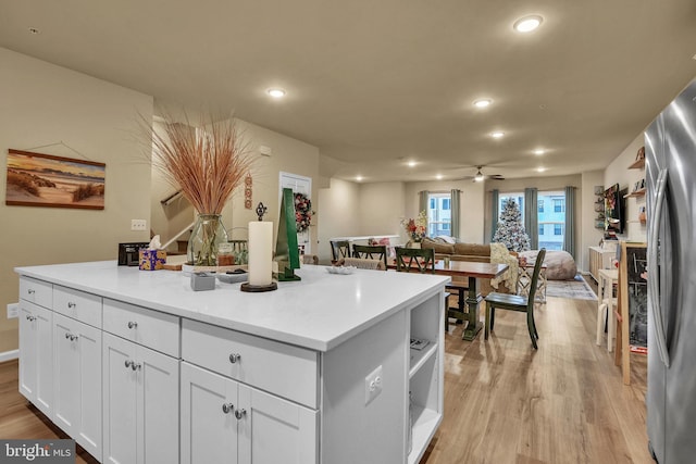 kitchen with white cabinetry, a center island, stainless steel fridge, ceiling fan, and light hardwood / wood-style floors