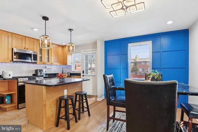 kitchen featuring pendant lighting, a breakfast bar, a center island, light hardwood / wood-style flooring, and appliances with stainless steel finishes