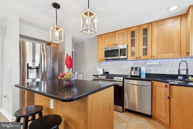 kitchen featuring a kitchen bar, appliances with stainless steel finishes, sink, pendant lighting, and a kitchen island