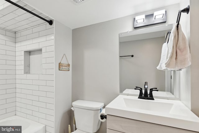 full bathroom featuring tiled shower / bath, vanity, and toilet