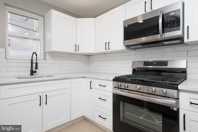 kitchen featuring white cabinets, backsplash, sink, and appliances with stainless steel finishes