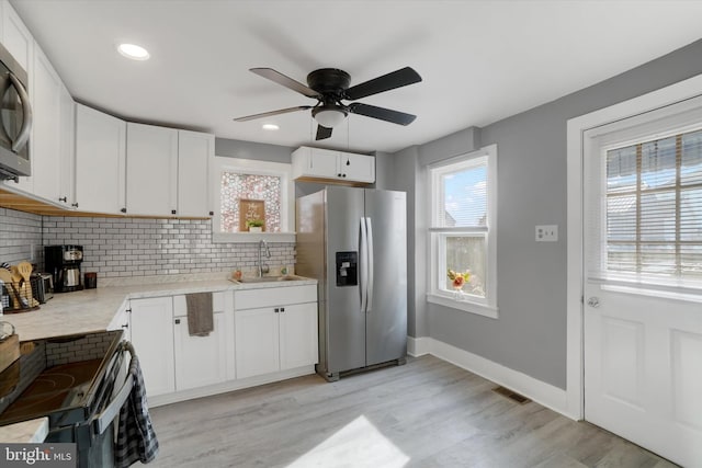 kitchen featuring sink, white cabinetry, light hardwood / wood-style flooring, stainless steel appliances, and decorative backsplash