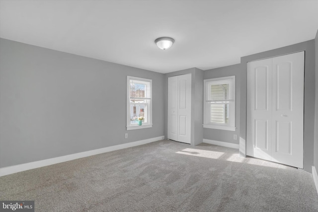 unfurnished bedroom with multiple closets and light carpet