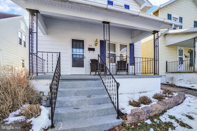 snow covered property entrance with a porch