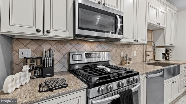 kitchen with white cabinetry, decorative backsplash, light stone counters, and appliances with stainless steel finishes