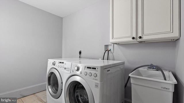 clothes washing area with cabinets, washer and dryer, and sink