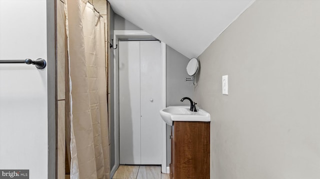 bathroom with a shower with shower curtain, vanity, and lofted ceiling