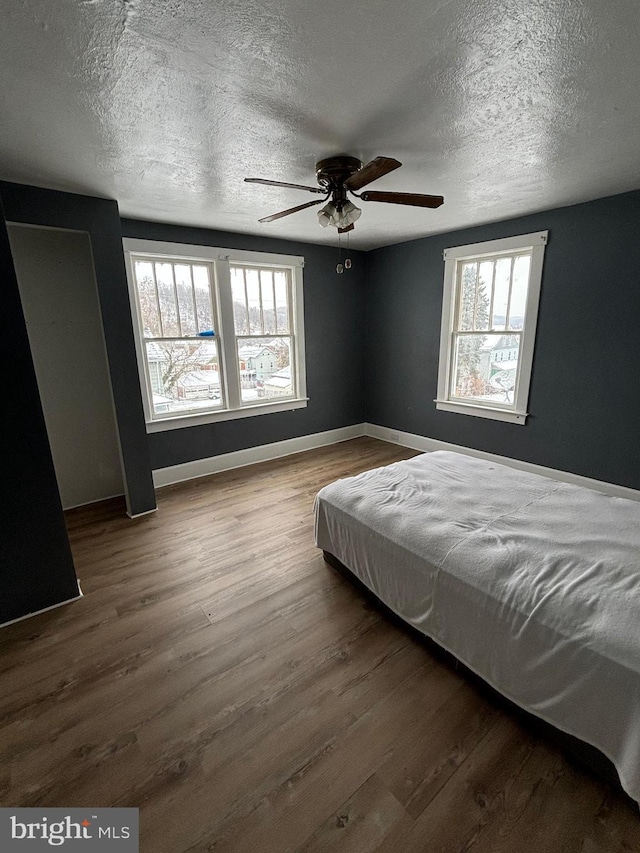 unfurnished bedroom featuring wood-type flooring, a textured ceiling, and ceiling fan